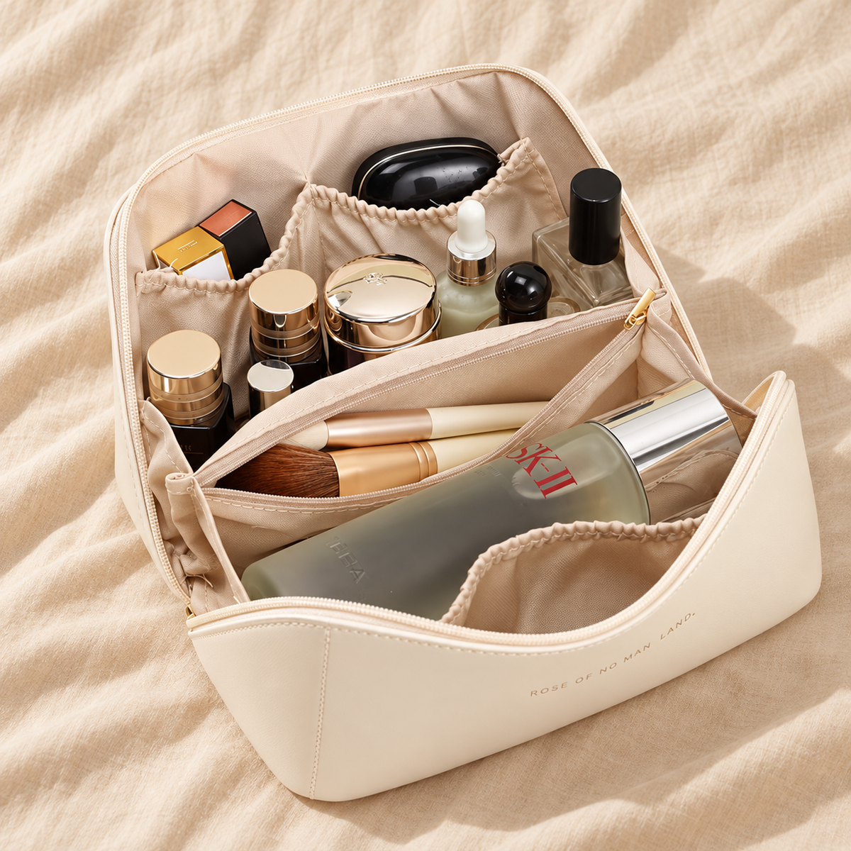Cream leather cosmetic bag open flat showing organised compartments filled with makeup and skincare