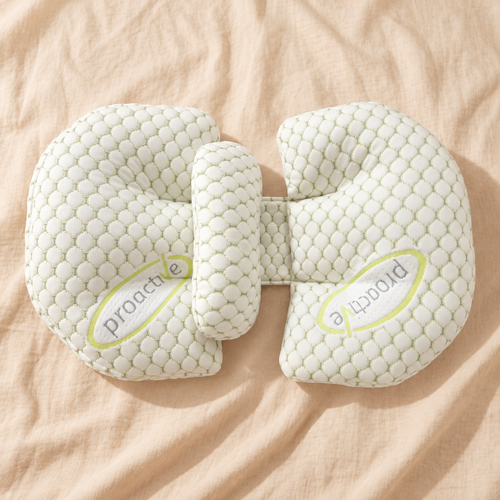 Adjustable U-shaped pregnancy support pillow in soft white quilted fabric on cream linen