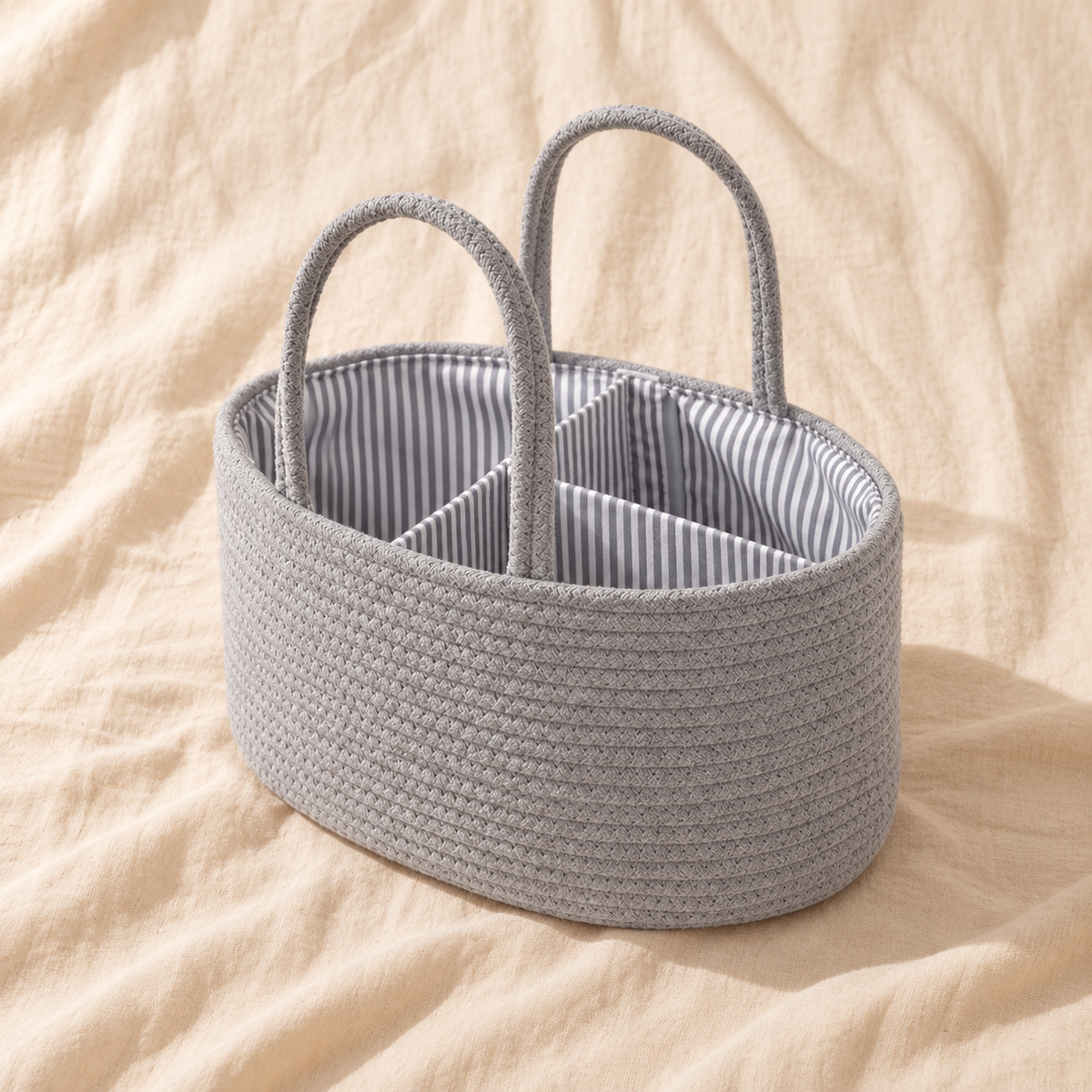 Grey cotton rope diaper caddy organiser with striped interior on cream linen