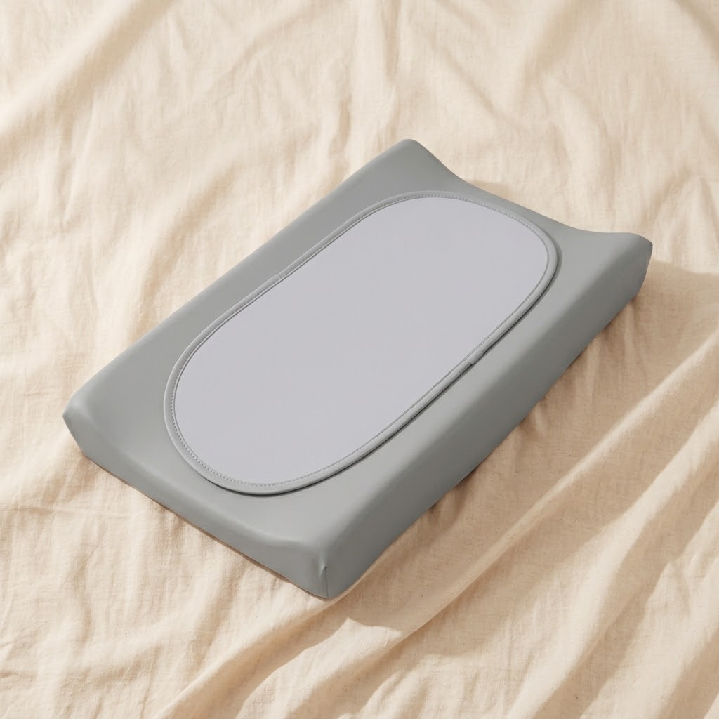 Grey waterproof baby changing pad with oval centre panel on cream linen background