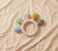 Baby sensory silicone ring teether with pastel coloured animal and textured attachments on cream linen